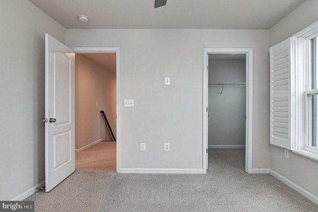 unfurnished bedroom featuring a spacious closet, light carpet, and a closet