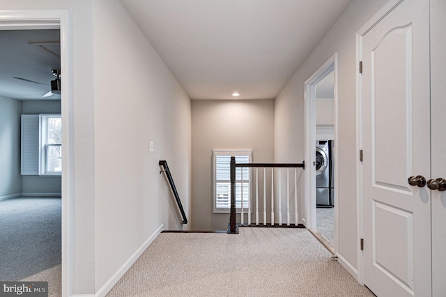 hall with a healthy amount of sunlight, washer / dryer, and light carpet