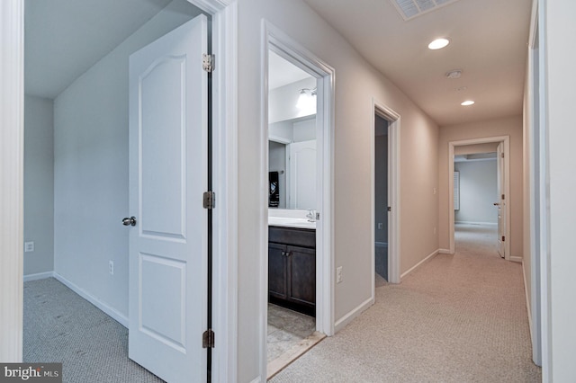 hall featuring sink and light carpet