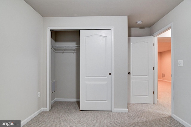 unfurnished bedroom featuring a closet and light carpet