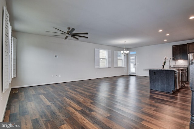 unfurnished living room featuring sink, dark hardwood / wood-style flooring, and ceiling fan with notable chandelier