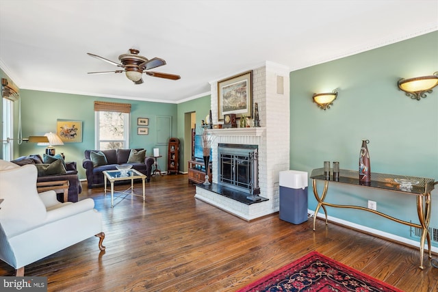 living room featuring a fireplace, crown molding, baseboards, and wood finished floors