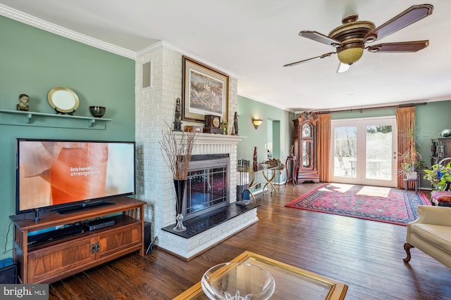 living area with a fireplace, ornamental molding, and wood finished floors