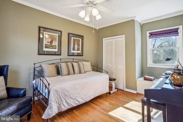 bedroom featuring crown molding, a closet, a ceiling fan, wood finished floors, and baseboards