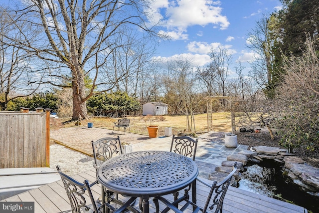 wooden deck featuring an outbuilding, outdoor dining area, a patio, and a storage shed