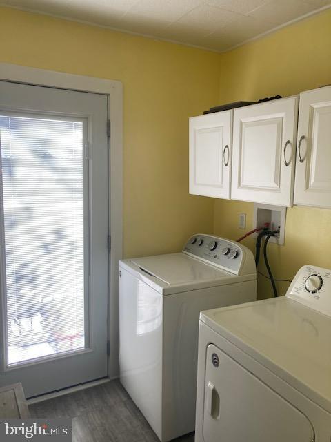 laundry room with cabinets, washing machine and dryer, and dark wood-type flooring