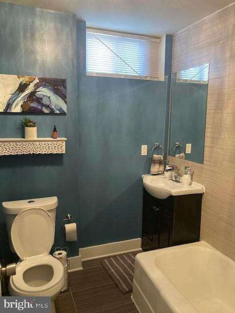 bathroom with vanity, a tub to relax in, and toilet