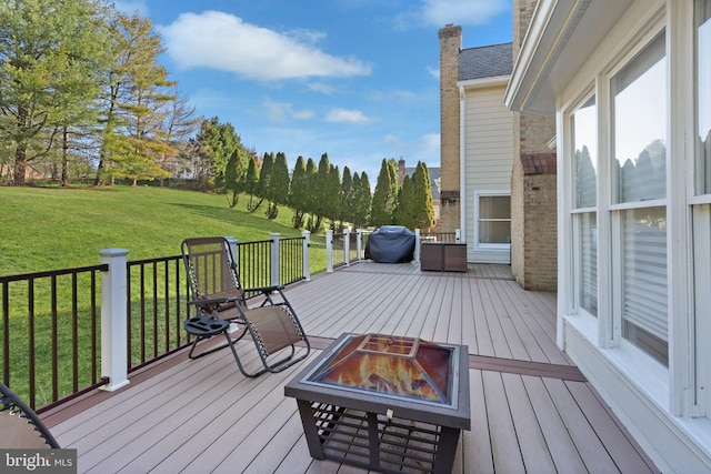 wooden deck with grilling area, a yard, and a fire pit