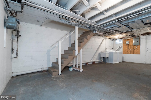 basement with sink, washing machine and clothes dryer, and electric panel