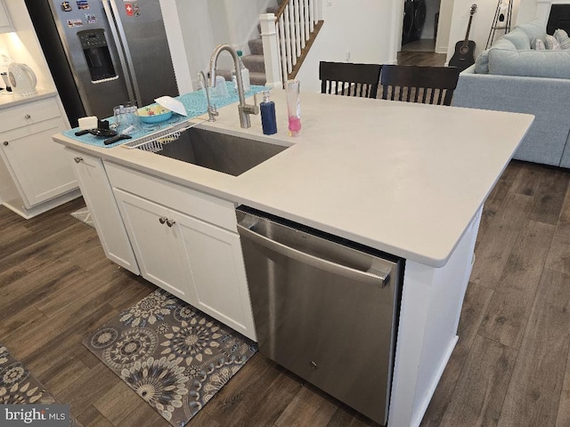 kitchen with appliances with stainless steel finishes, dark hardwood / wood-style floors, a center island with sink, and white cabinets