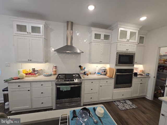 kitchen featuring white cabinetry, appliances with stainless steel finishes, dark hardwood / wood-style floors, and wall chimney range hood