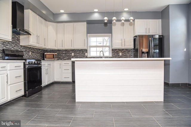 kitchen with wall chimney range hood, stainless steel appliances, a center island, white cabinets, and decorative light fixtures