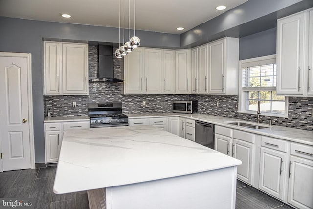 kitchen with a kitchen island, appliances with stainless steel finishes, sink, white cabinets, and wall chimney range hood