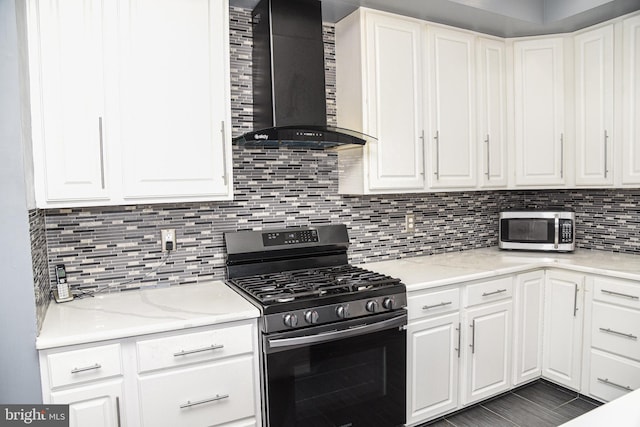 kitchen with white cabinetry, stainless steel appliances, light stone countertops, and wall chimney range hood