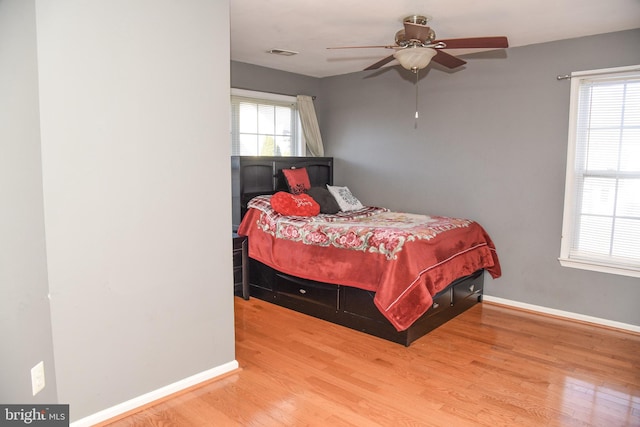 bedroom featuring ceiling fan, wood-type flooring, and multiple windows