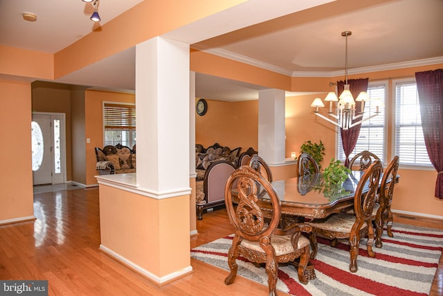 dining space with ornamental molding, light hardwood / wood-style flooring, and a notable chandelier