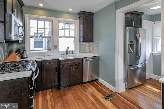 kitchen featuring light wood-style flooring, stainless steel appliances, a sink, visible vents, and light countertops