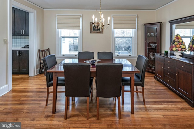 dining area featuring a healthy amount of sunlight, a chandelier, wood finished floors, and ornamental molding