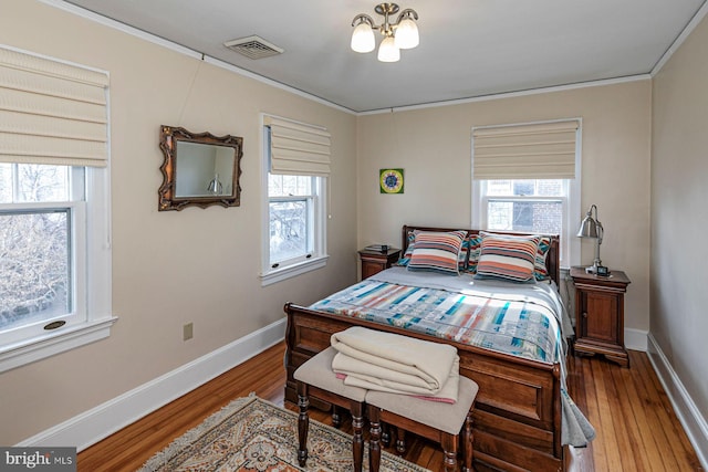 bedroom featuring visible vents, crown molding, multiple windows, and wood finished floors