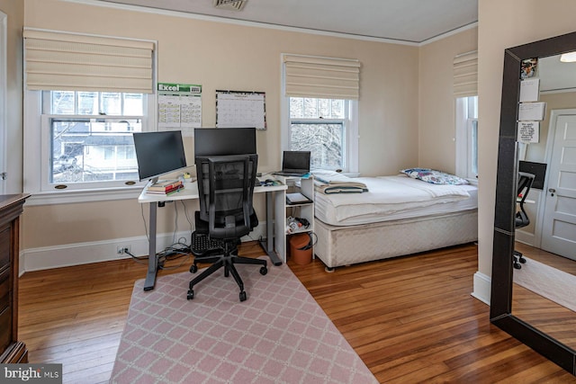 bedroom with visible vents, crown molding, baseboards, and hardwood / wood-style flooring