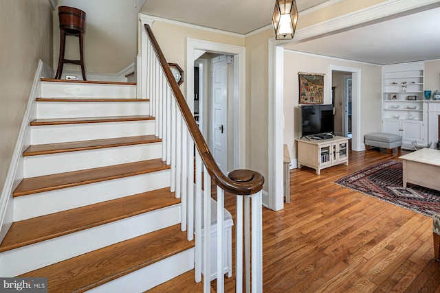 stairs featuring crown molding, baseboards, and wood finished floors