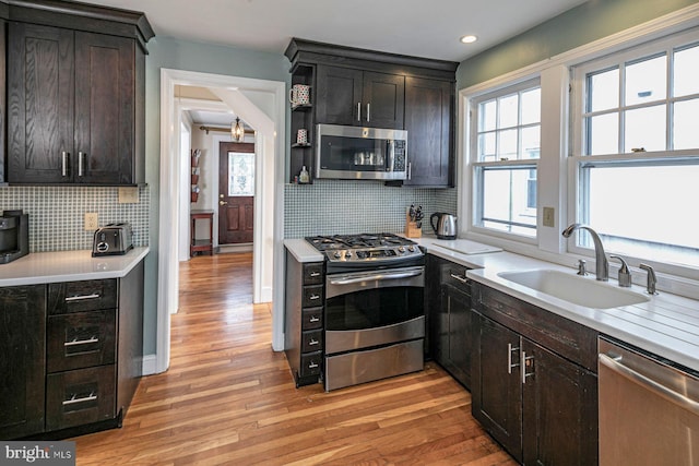 kitchen featuring stainless steel appliances, light wood-style floors, light countertops, and a sink