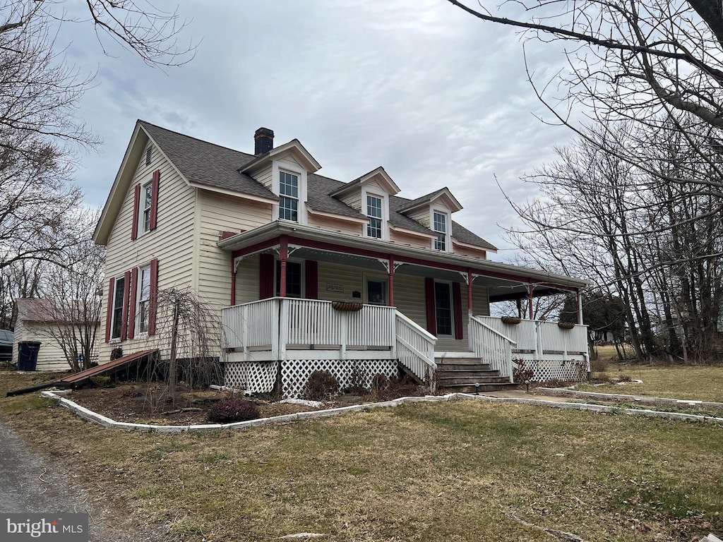 view of front facade with a porch, a front yard, and a shingled roof