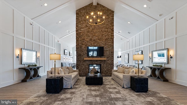 living room with a stone fireplace, an inviting chandelier, wood-type flooring, high vaulted ceiling, and beamed ceiling