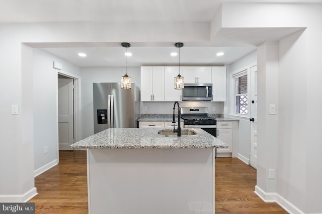 kitchen featuring sink, light stone counters, an island with sink, stainless steel appliances, and white cabinets