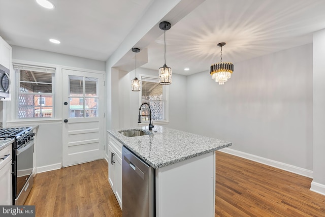 kitchen with sink, pendant lighting, stainless steel appliances, light stone countertops, and white cabinets