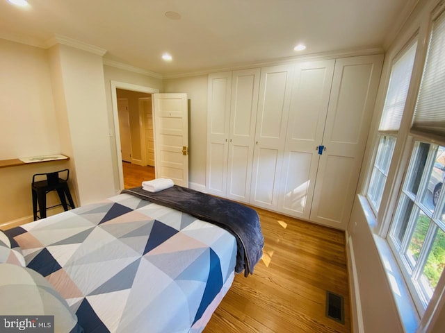 bedroom with crown molding, light hardwood / wood-style floors, and a closet