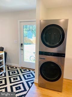 laundry room with wood-type flooring and stacked washer / drying machine