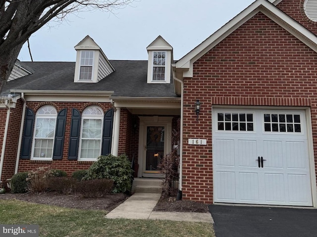 view of front of property with aphalt driveway, an attached garage, brick siding, and a shingled roof