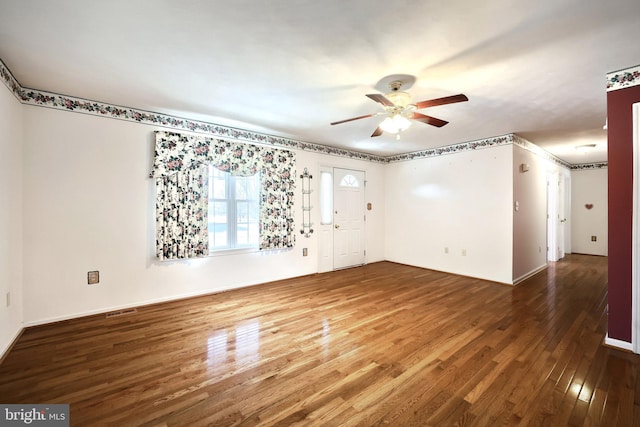 spare room with ceiling fan, wood finished floors, visible vents, and baseboards