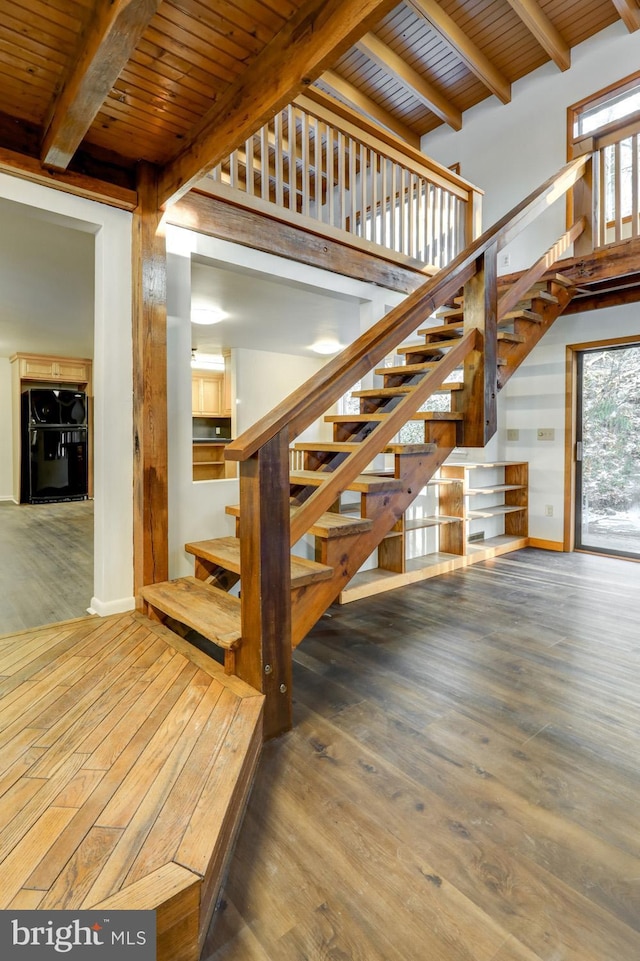 stairs featuring beamed ceiling, a healthy amount of sunlight, hardwood / wood-style floors, and wood ceiling