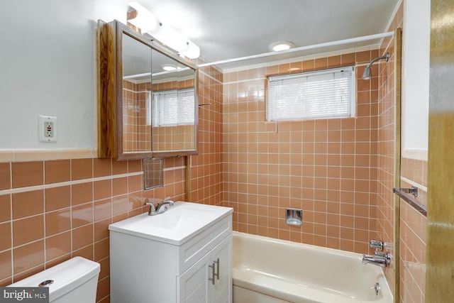 full bathroom featuring tiled shower / bath combo, vanity, tile walls, and toilet