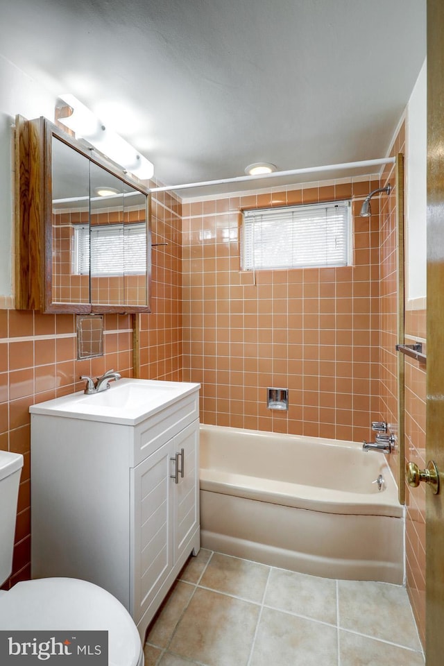 full bathroom featuring tile walls, tile patterned floors, toilet, and tiled shower / bath