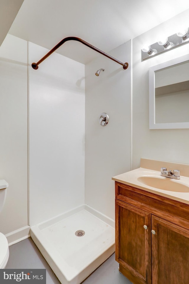 bathroom featuring vanity, walk in shower, and toilet