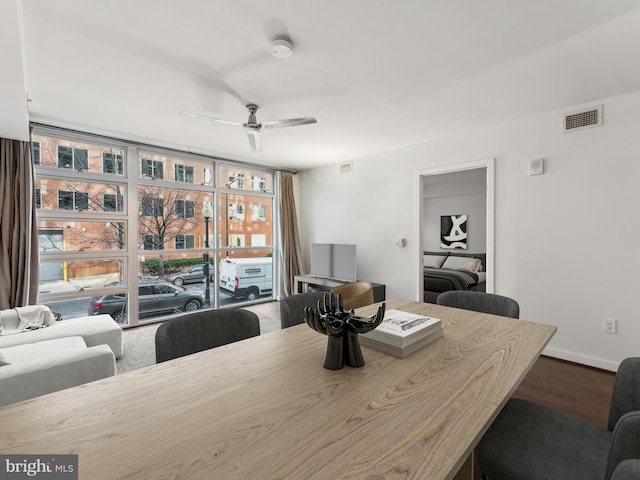 dining space with hardwood / wood-style floors, a wall of windows, and ceiling fan