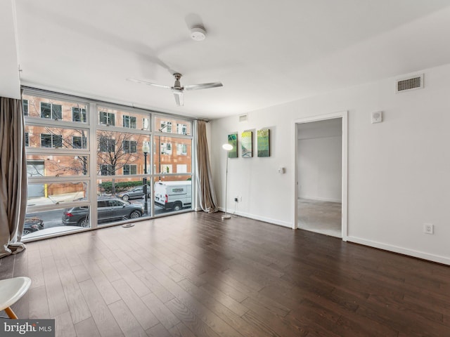 empty room featuring expansive windows, dark hardwood / wood-style floors, and ceiling fan