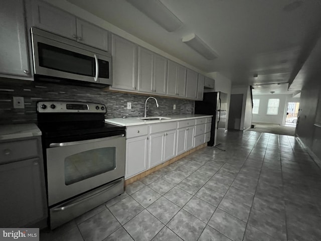 kitchen featuring tasteful backsplash, stainless steel appliances, light tile patterned flooring, and sink