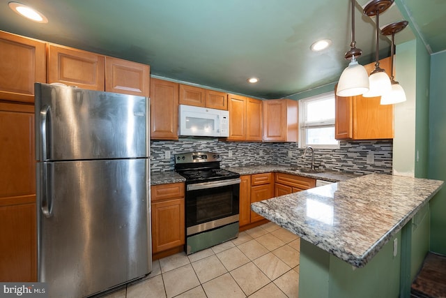 kitchen featuring sink, backsplash, stainless steel appliances, decorative light fixtures, and kitchen peninsula