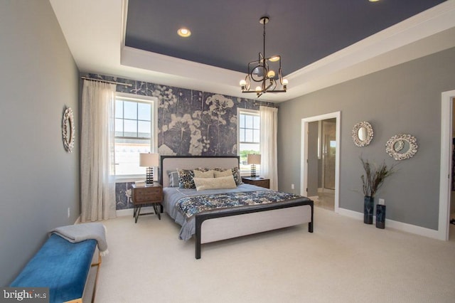 carpeted bedroom with an inviting chandelier, a tray ceiling, and ensuite bathroom