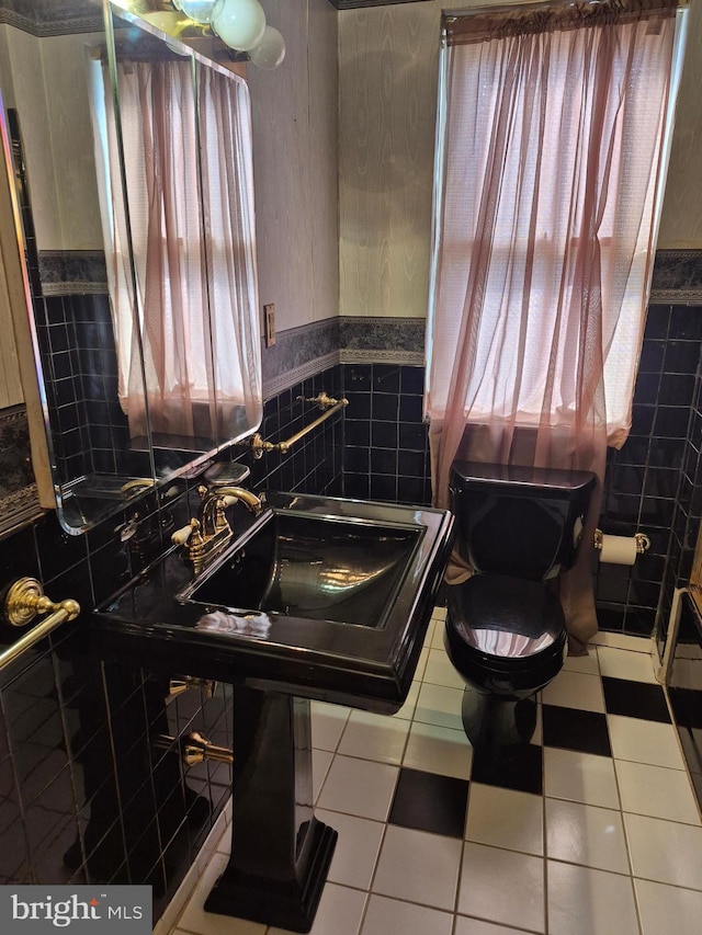 bathroom with toilet, a wainscoted wall, tile patterned flooring, and tile walls