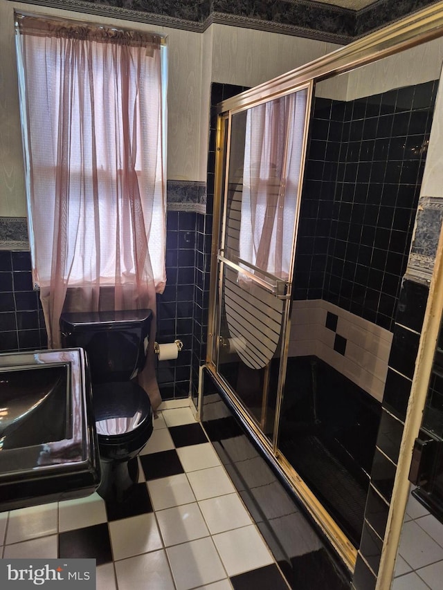 full bathroom with toilet, a wainscoted wall, tile walls, a shower stall, and tile patterned floors