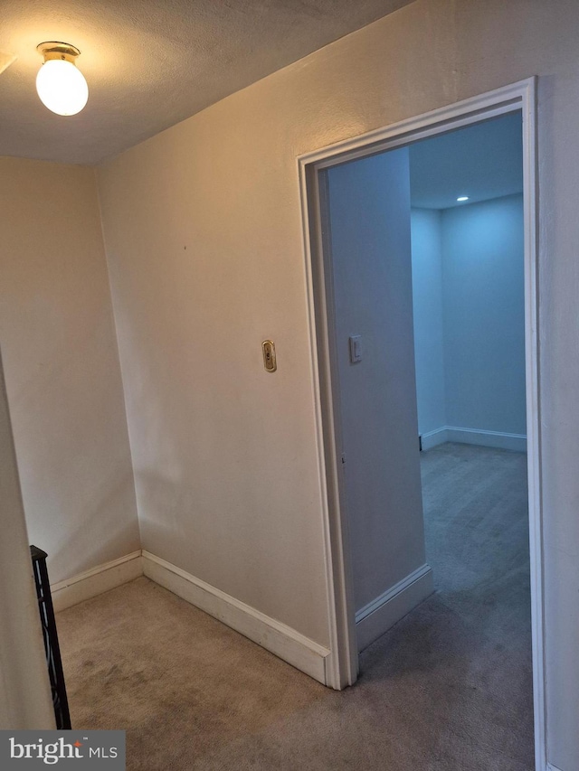 interior space featuring a textured ceiling, carpet, and baseboards