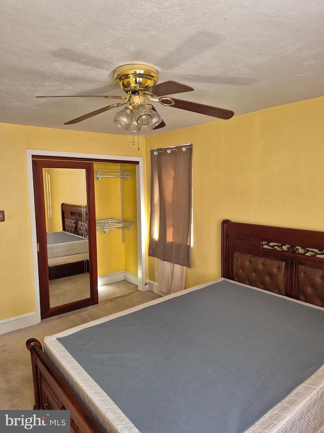 unfurnished bedroom with carpet floors, ceiling fan, a textured ceiling, and a closet