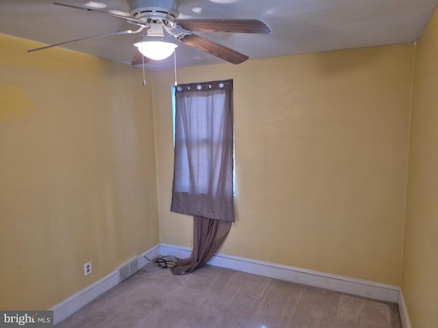 carpeted empty room featuring a ceiling fan and baseboards