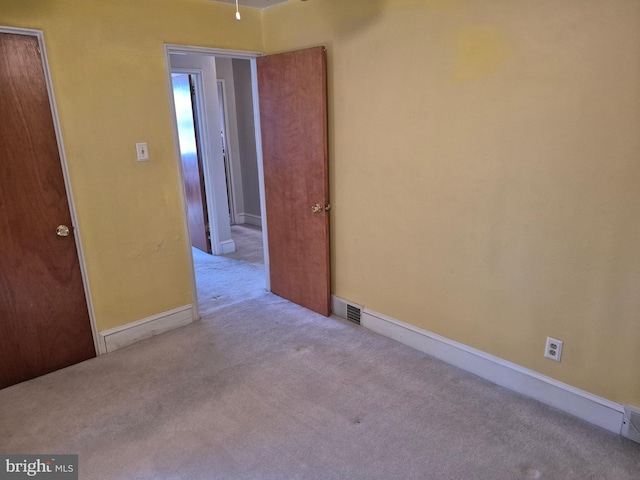 spare room featuring carpet, visible vents, and baseboards