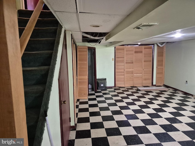 finished basement featuring stairway, visible vents, and tile patterned floors